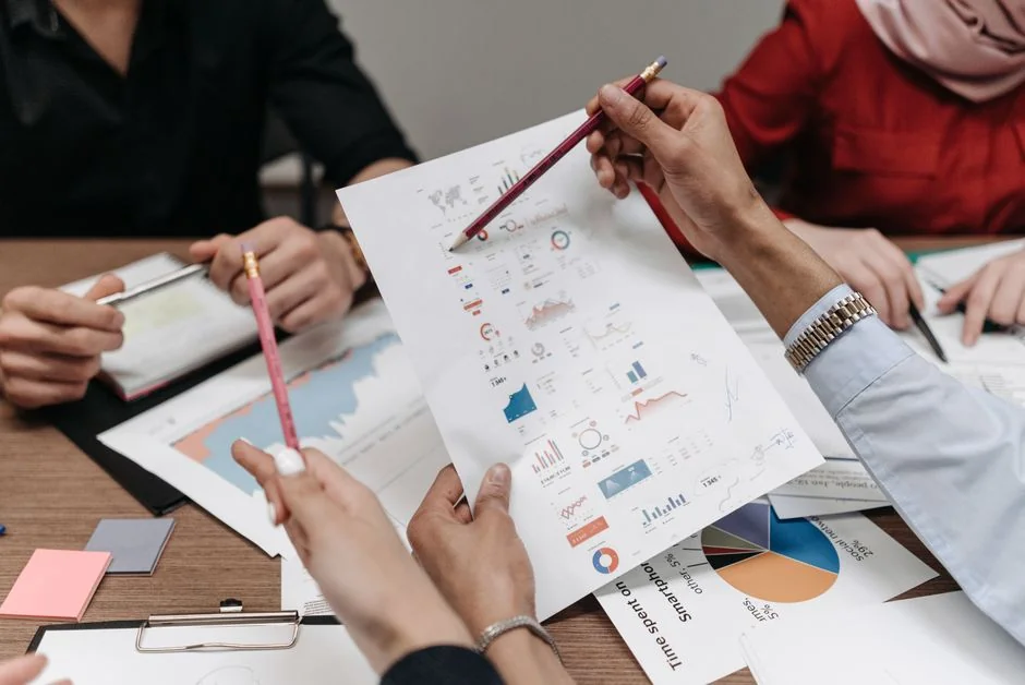 Personne analysant des graphiques d’entreprise avec un smartphone et un ordinateur portable sur le bureau.